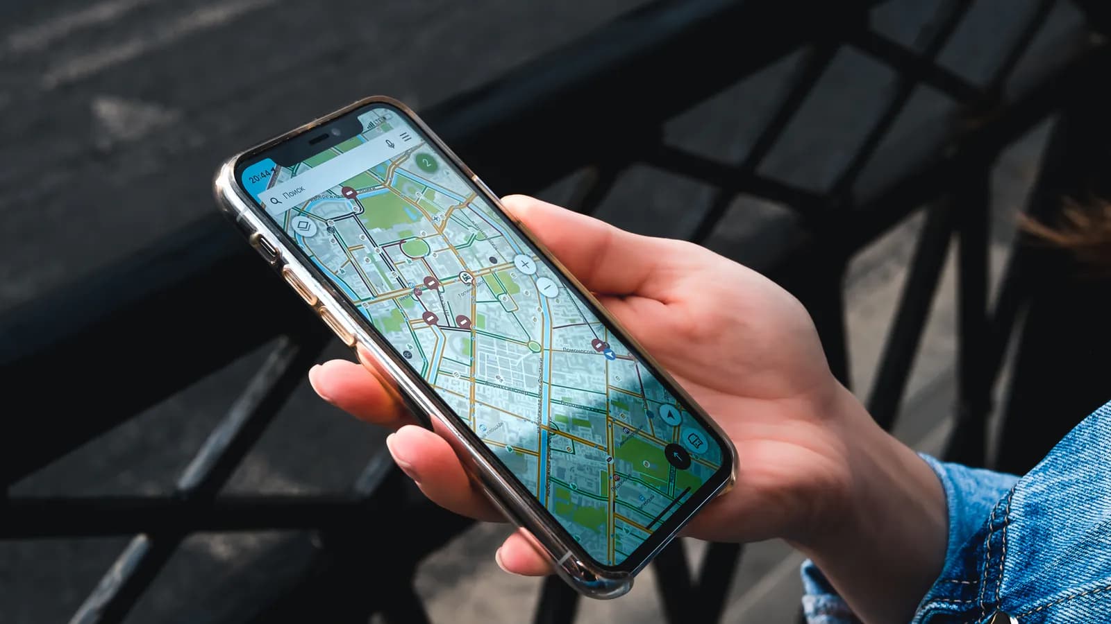 Əldə tutulan telefonun ekranında şəhər xəritəsi açıqdır: yuxarıda axtarış sahəsi, xəritədə isə küçələr boyu səpələnmiş biznes nişanları görünür.