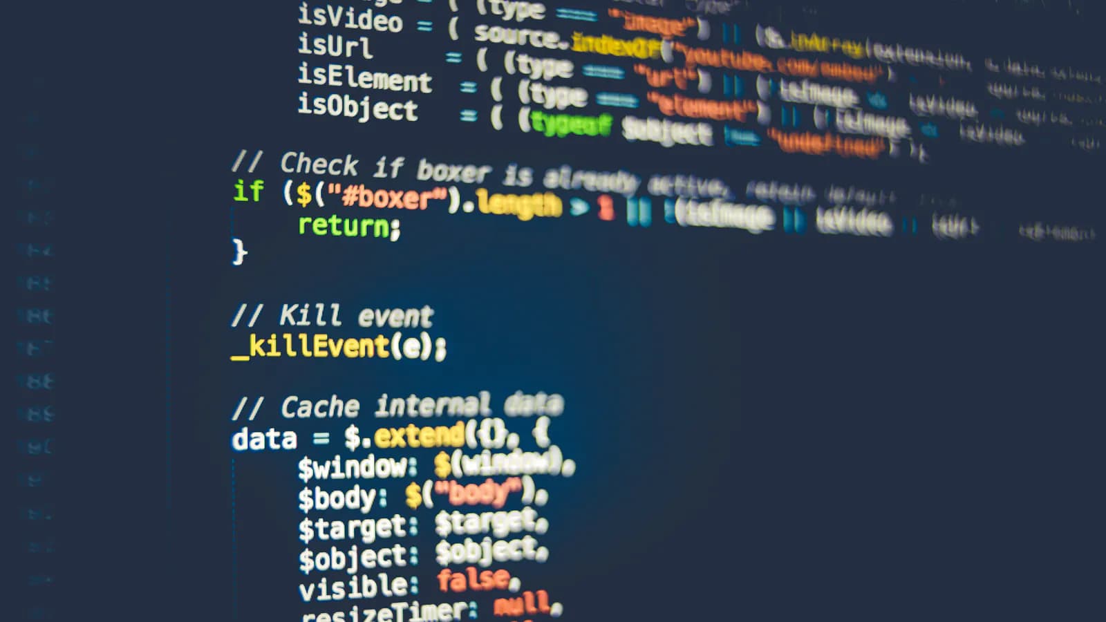 Monitor ekranında JavaScript kodu sətirləri yaxından — şərt yoxlamaları və hadisə funksiyaları önə, arxa fon isə bulanıq.