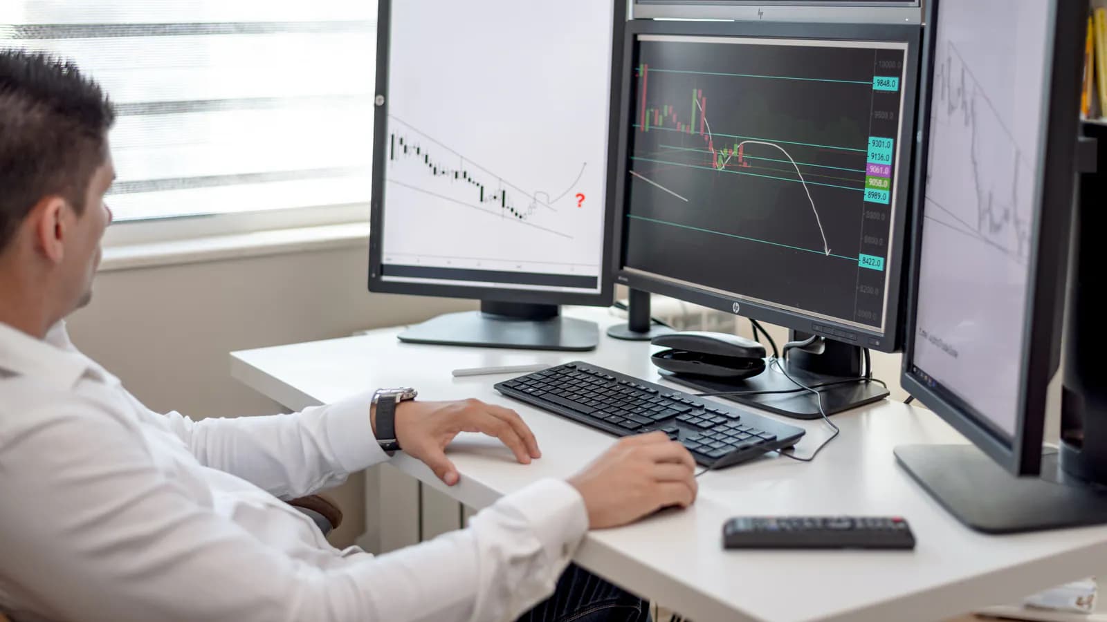 Ofis masasında bir neçə monitorda canlı analitika göstəriciləri olan idarəetmə paneli.