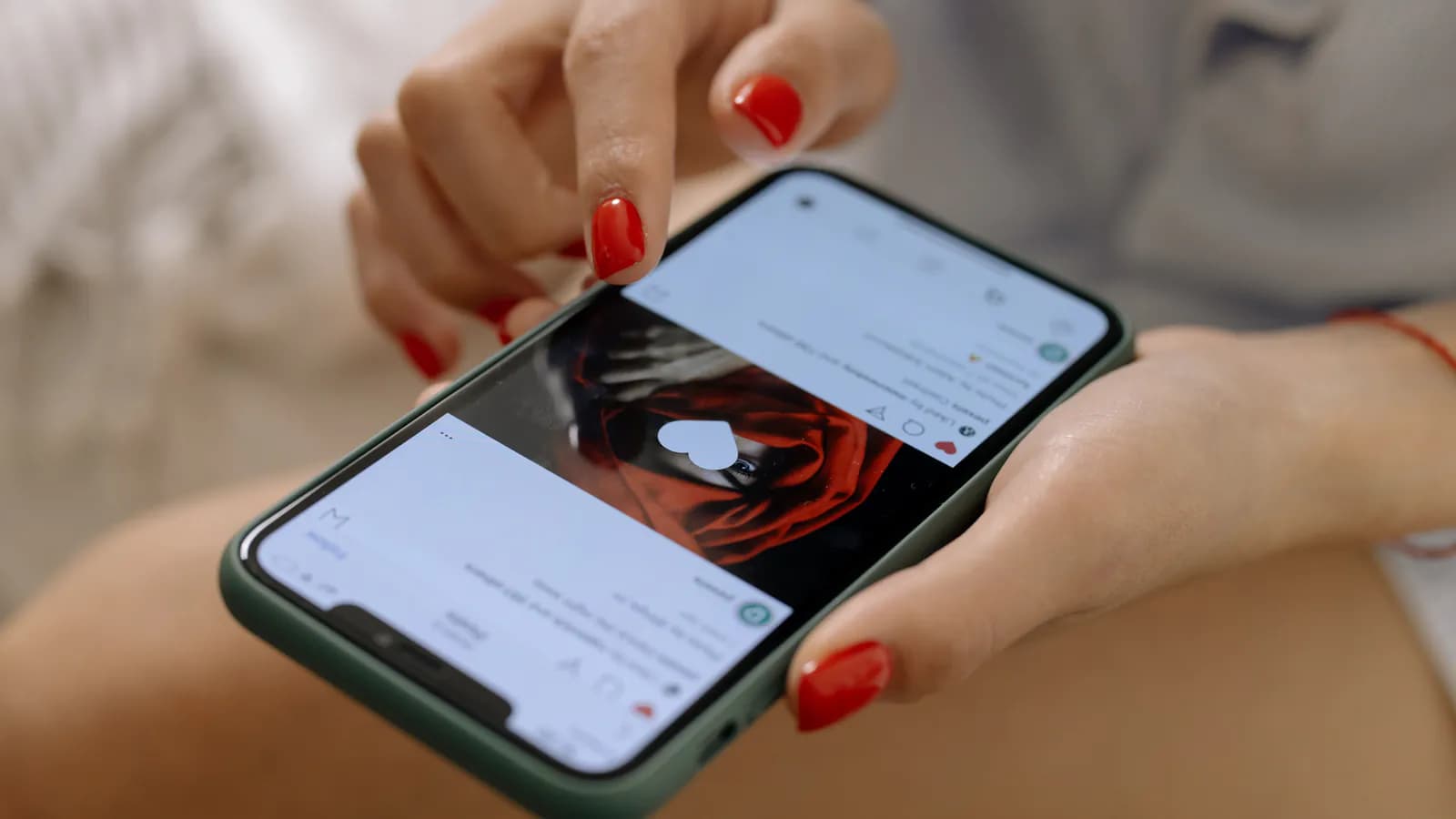 Bir əl smartfonu tutub Instagram lentini sürüşdürür, ekranda kvadrat foto kartları bir-birinin ardınca görünür.