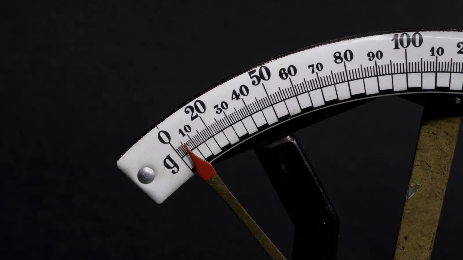 Qara fonda analoq tərəzinin şkalası: qırmızı əqrəb hələ sıfırın üstündə dayanıb, bölgülər 0-dan 100-ə qədər uzanır — ölçmə başlamayanda rəqəm də yoxdur.