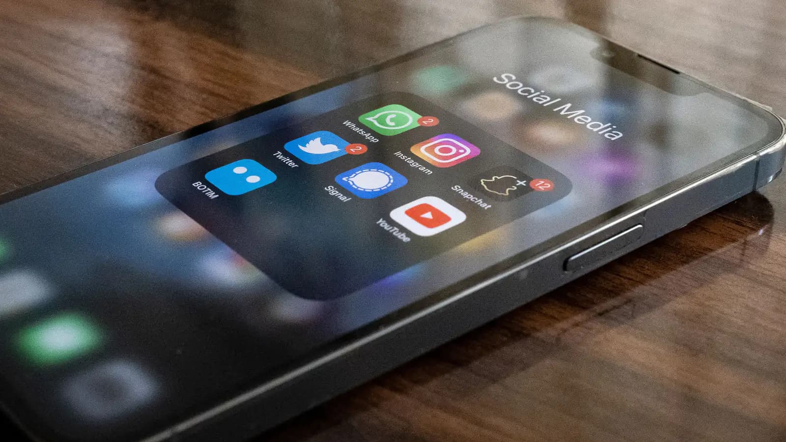 Smartfon ekranında bir neçə sosial media tətbiqinin ikonaları yaxın planda, barmaq ekrana toxunmaq üzrədir.