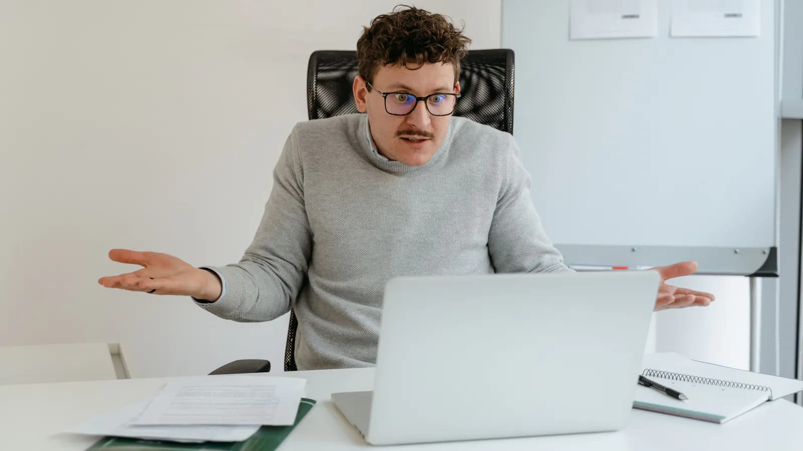 Laptop ekranına baxıb çaşqın vəziyyətdə əlini alnına aparan bir insan, ekranda mürəkkəb görünüşlü sayt interfeysi seçilir.