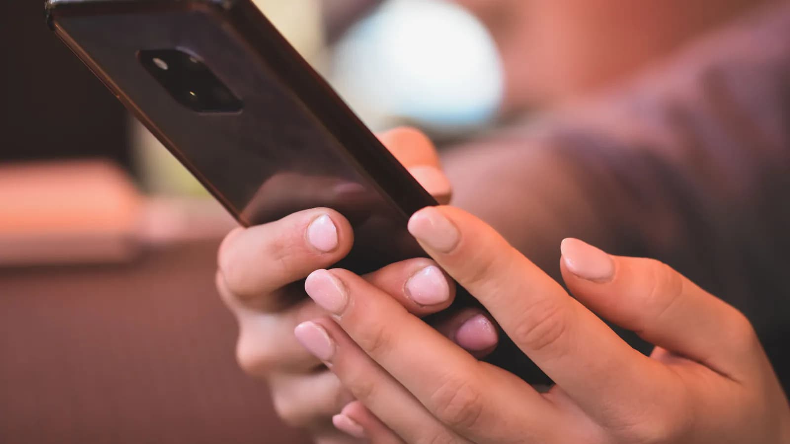 Yaxın planda bir əl smartfonun ekranında mesaj yazır, barmaqlar klaviatura üzərindədir.